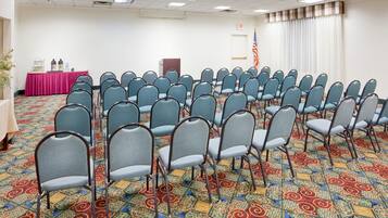 A conference room with rows of chairs, a table with supplies, and an American flag.