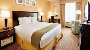 Una habitación de hotel con una cama grande, mesitas de noche, un escritorio, una silla y un televisor.