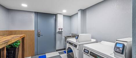 A laundry room with a washing machine, dryer, and a wooden bench.