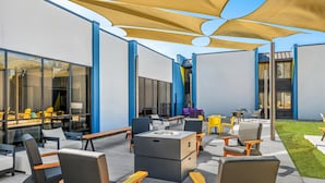 An outdoor seating area with modern furniture and a large umbrella providing shade. - Sonesta Select Hotels Statesville (Statesville)