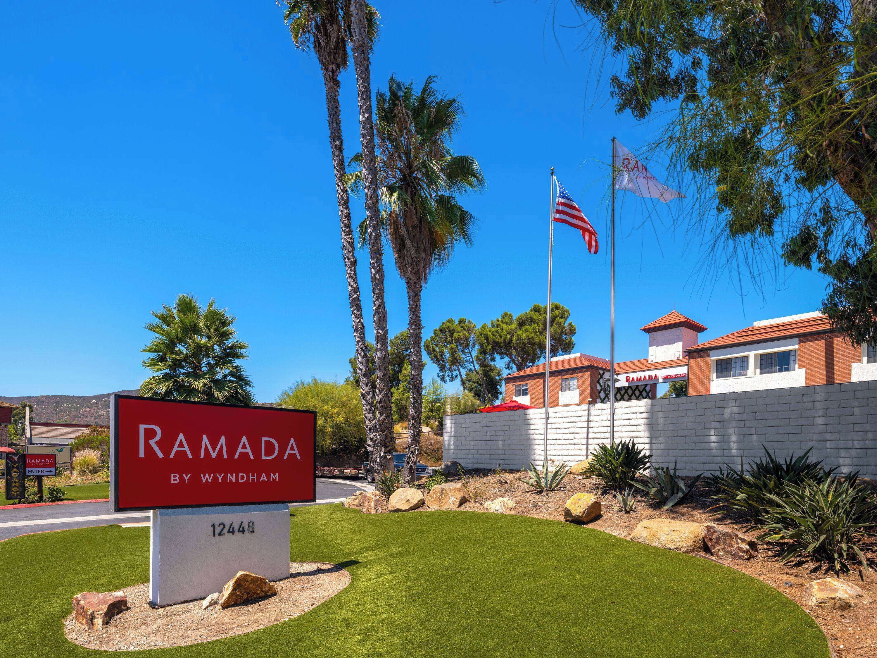 A sign for Ramada by Wyndham hotel with a clear view of the building and surrounding landscaping.
