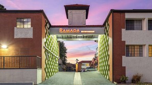 Una entrada protegida por una verja a un edificio con un letrero que dice "RAMADA BY WYNDHAM".