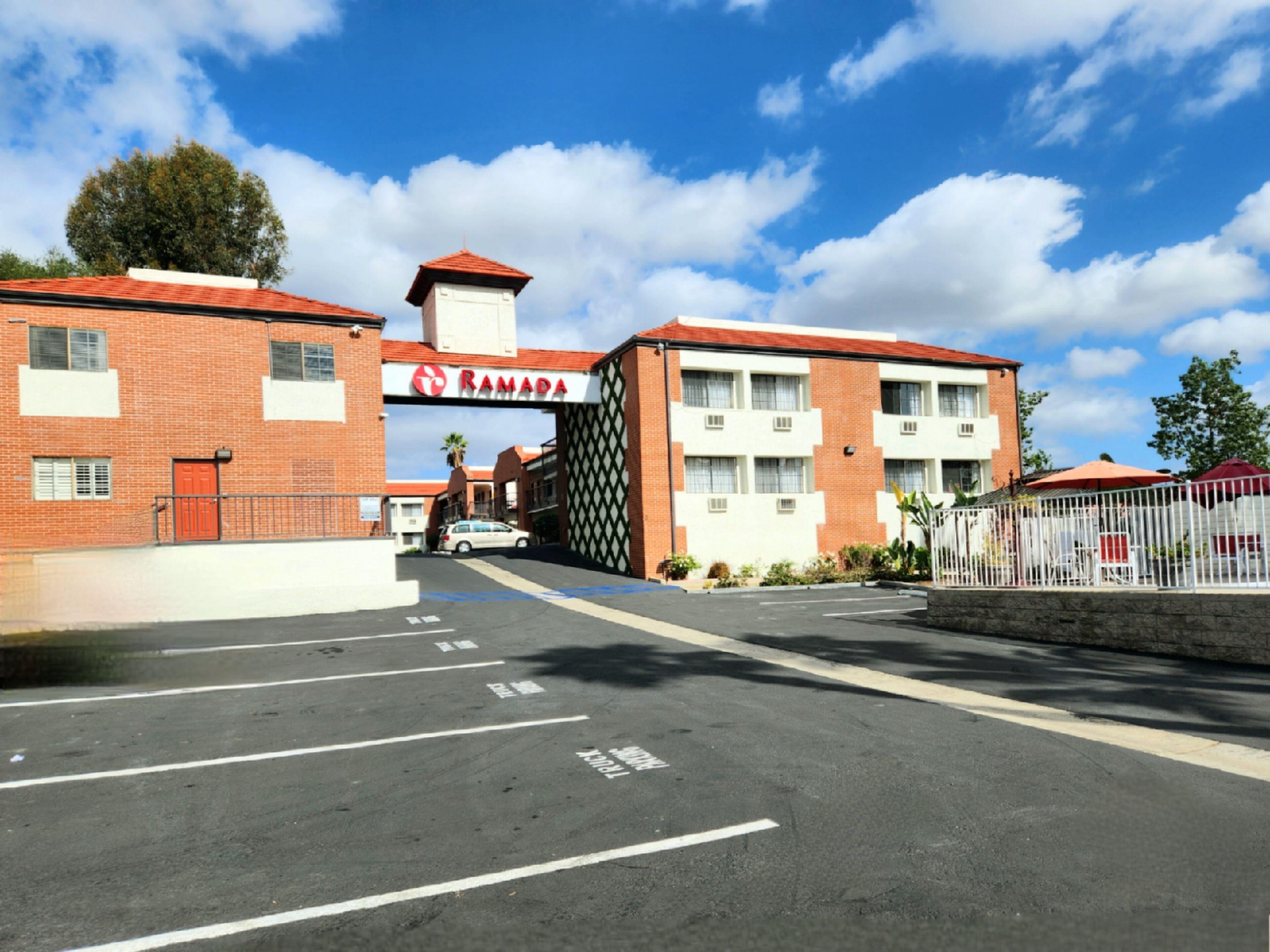 Un estacionamiento con un edificio que lleva la etiqueta "RAMADA" al fondo.
