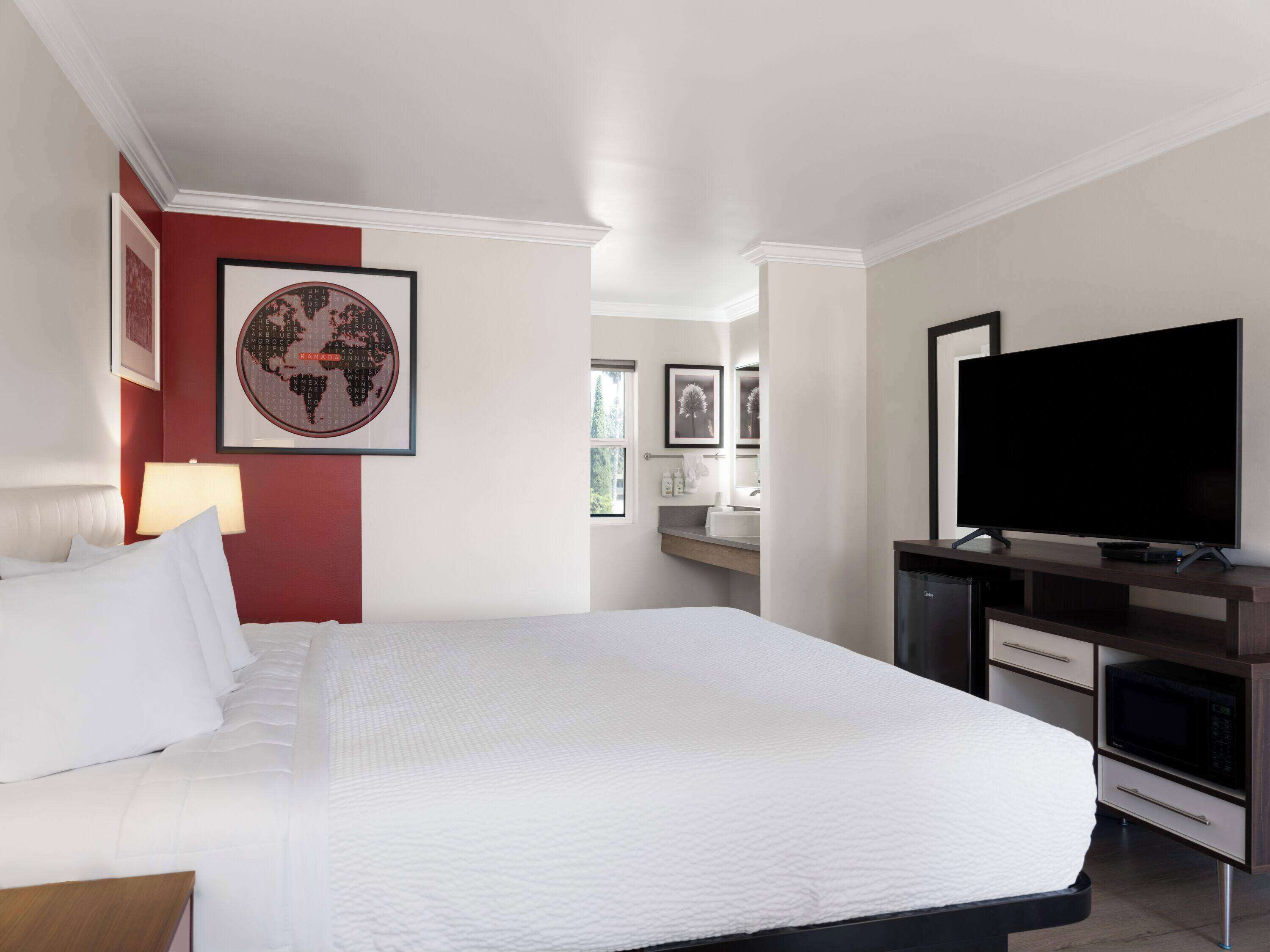 Habitación de hotel con una cama grande, un televisor de pantalla plana, un escritorio con computadora y una ventana.