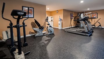 Une salle de sport équipée de divers appareils d’exercice, notamment des tapis de course, un vélo elliptique et un vélo d’appartement.
