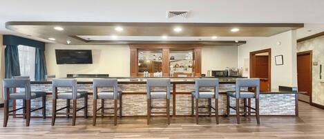 A modern kitchen with a bar area, equipped with a microwave, oven, and various kitchen appliances.