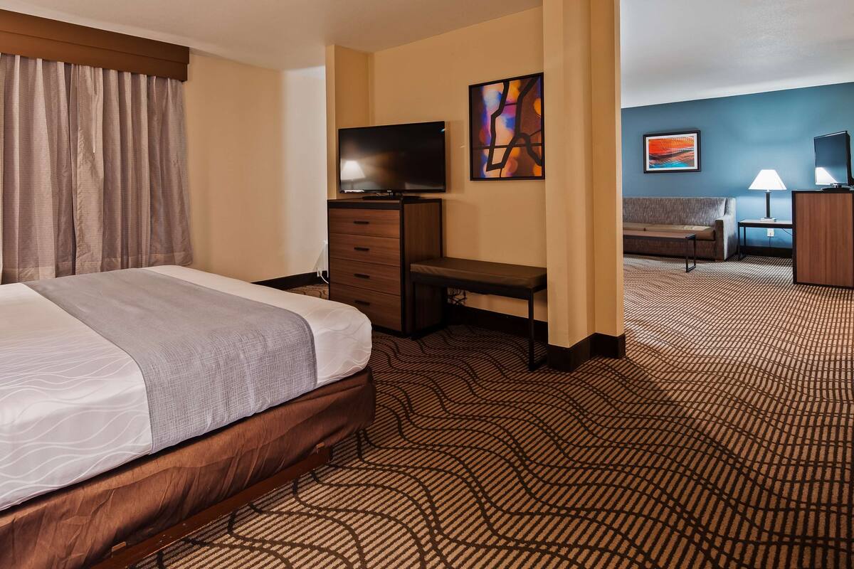 A hotel room with a bed, a desk, a television, and a sofa.