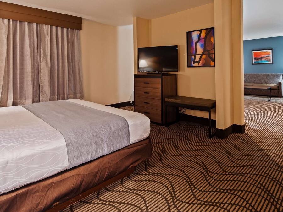 A hotel room with a bed, a desk, a television, and a sofa.