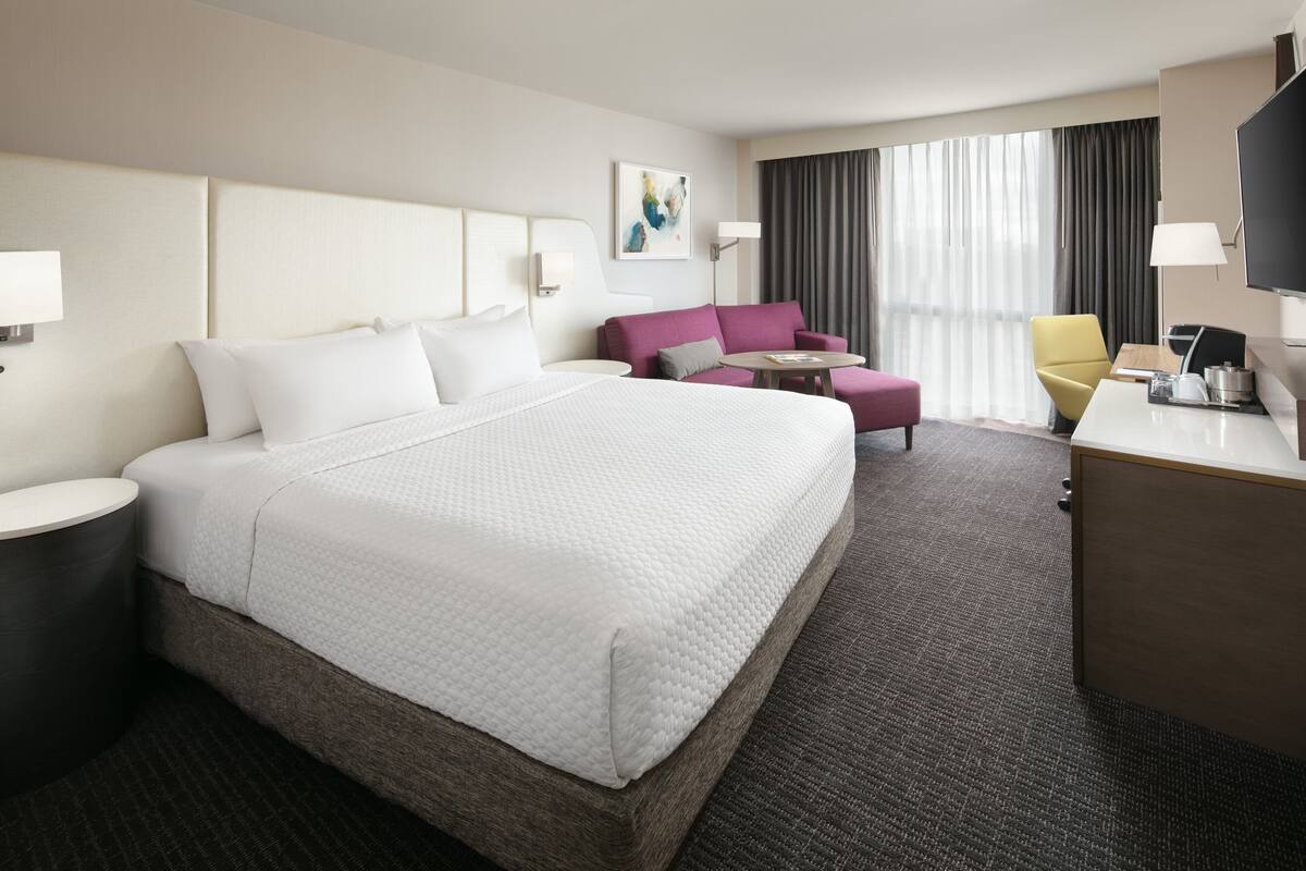 Een hotelkamer met een groot bed, een bureau, een stoel en een klein tafeltje.