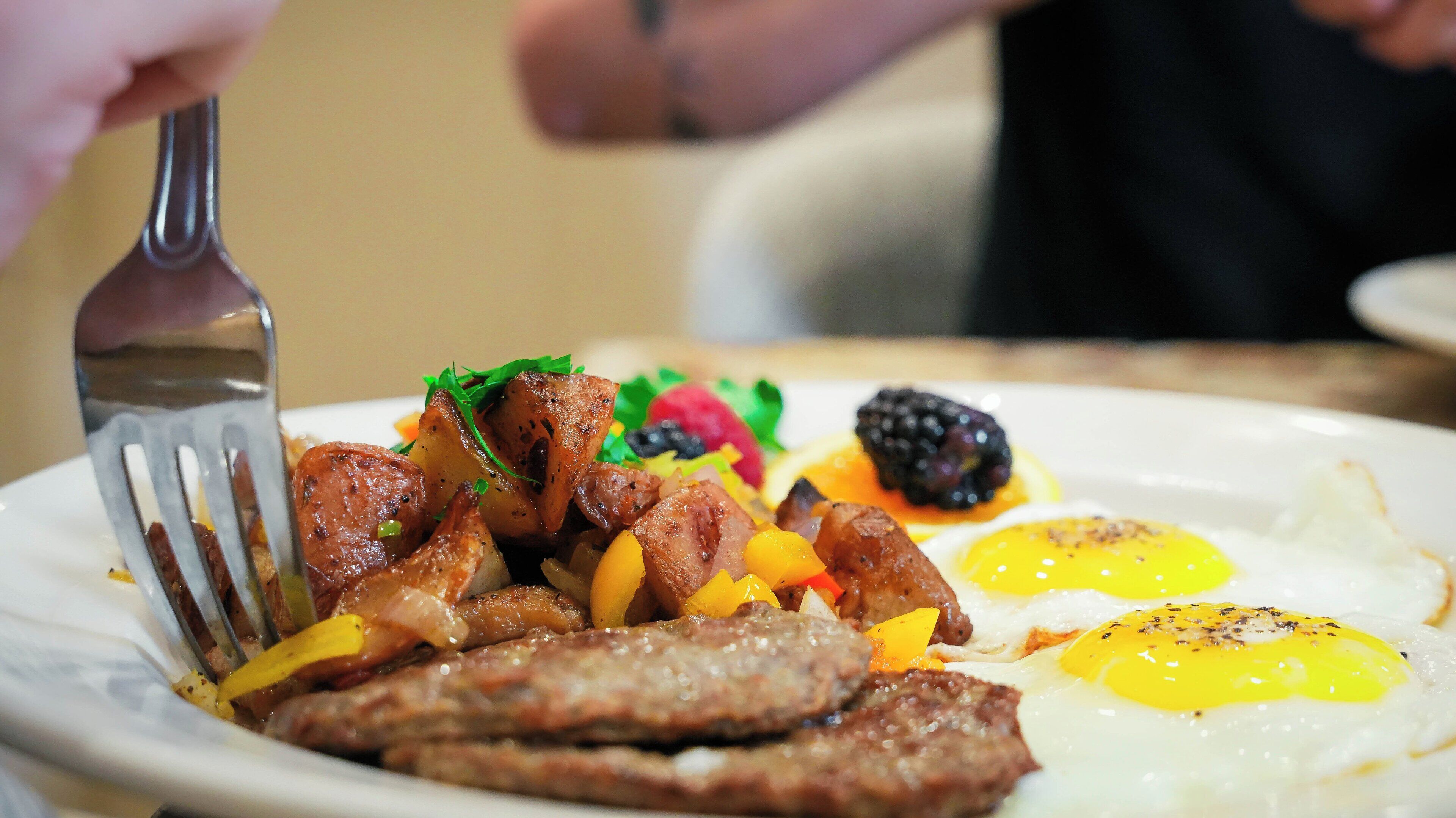 Un plato de desayuno con salchichas, huevos y fruta.