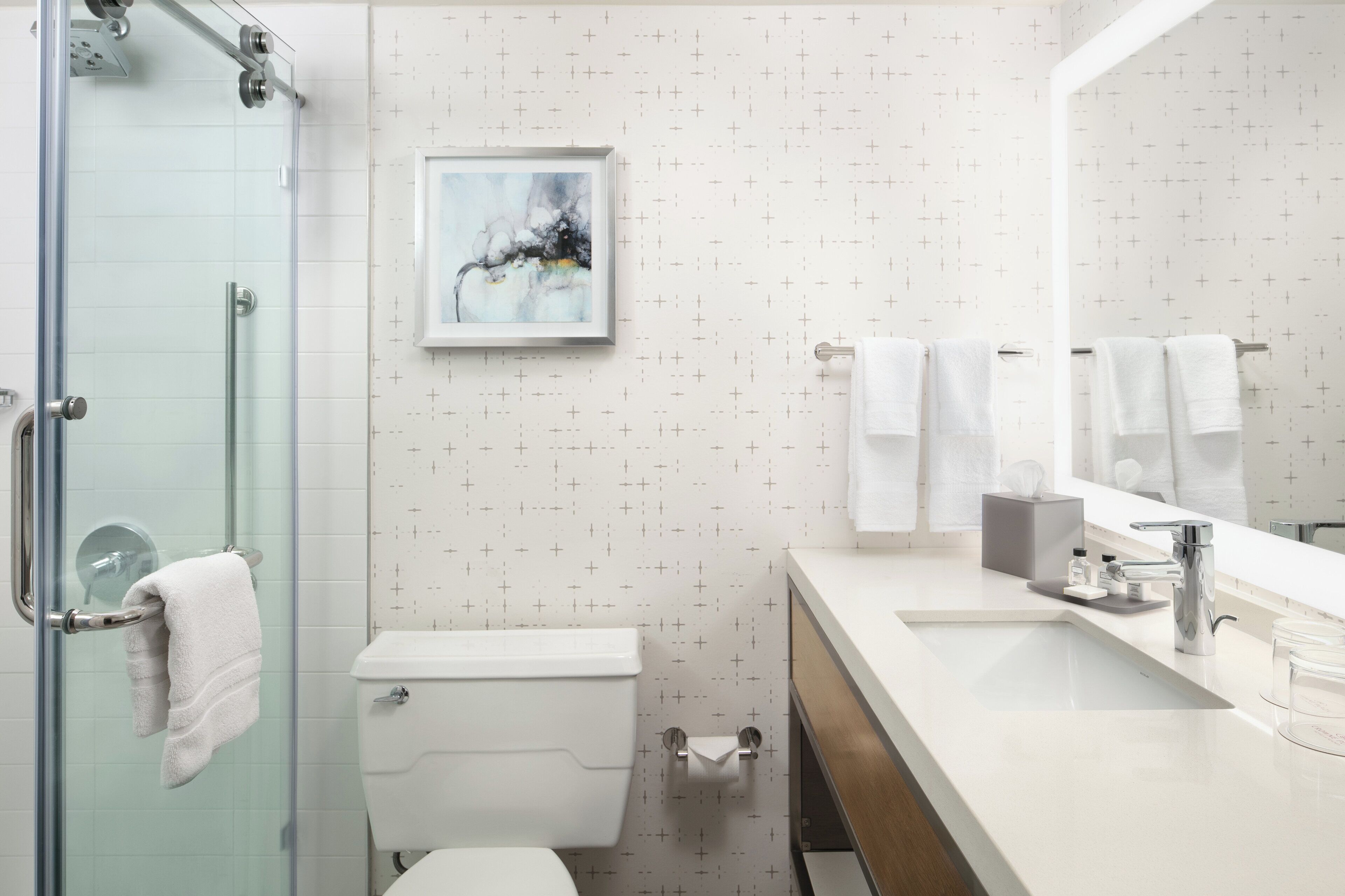 Une salle de bain moderne avec une douche à parois de verre, des toilettes, un lavabo avec un meuble-vasque et un grand miroir.