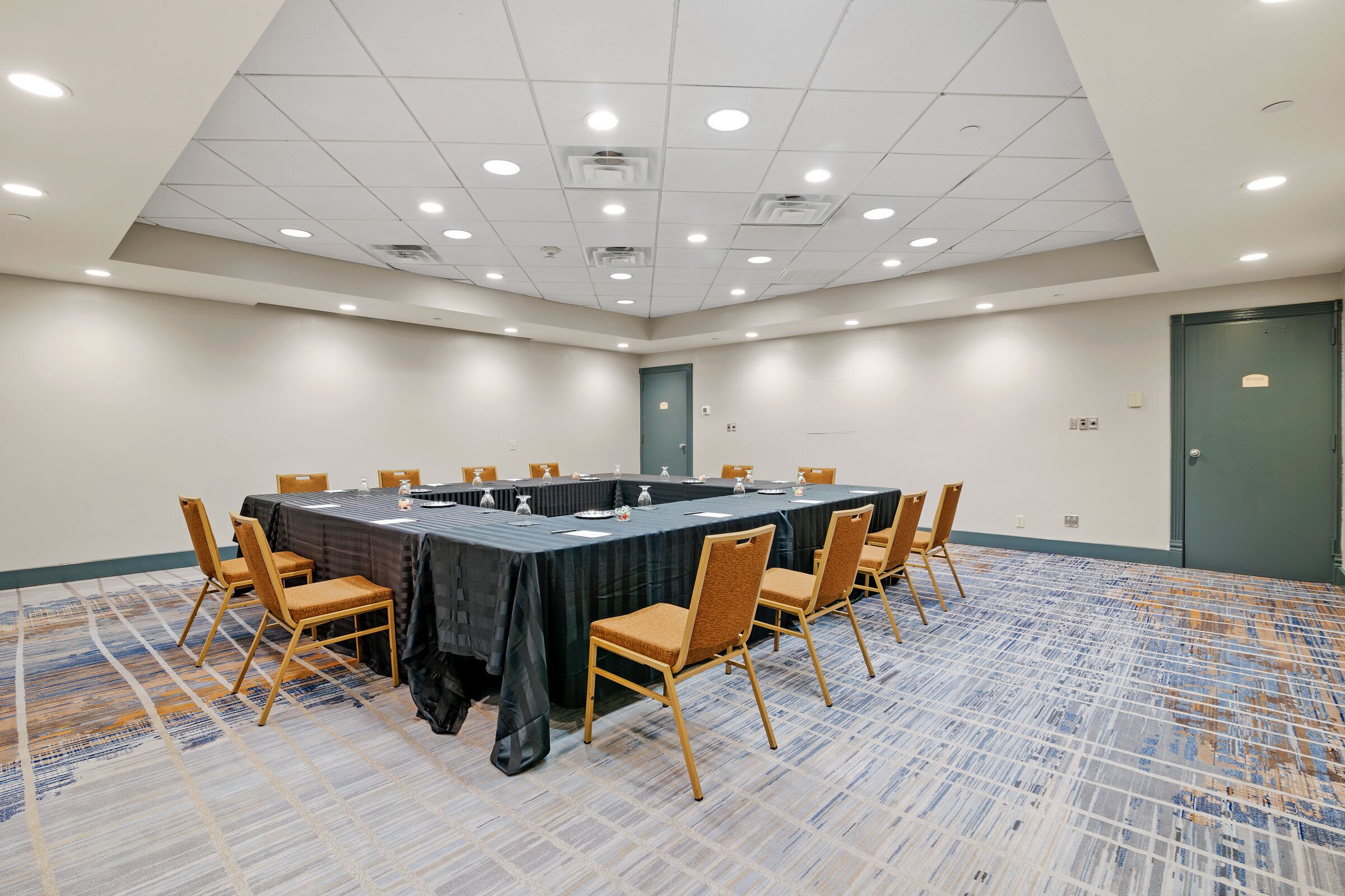 A conference room with a long table, chairs, and a carpeted floor.