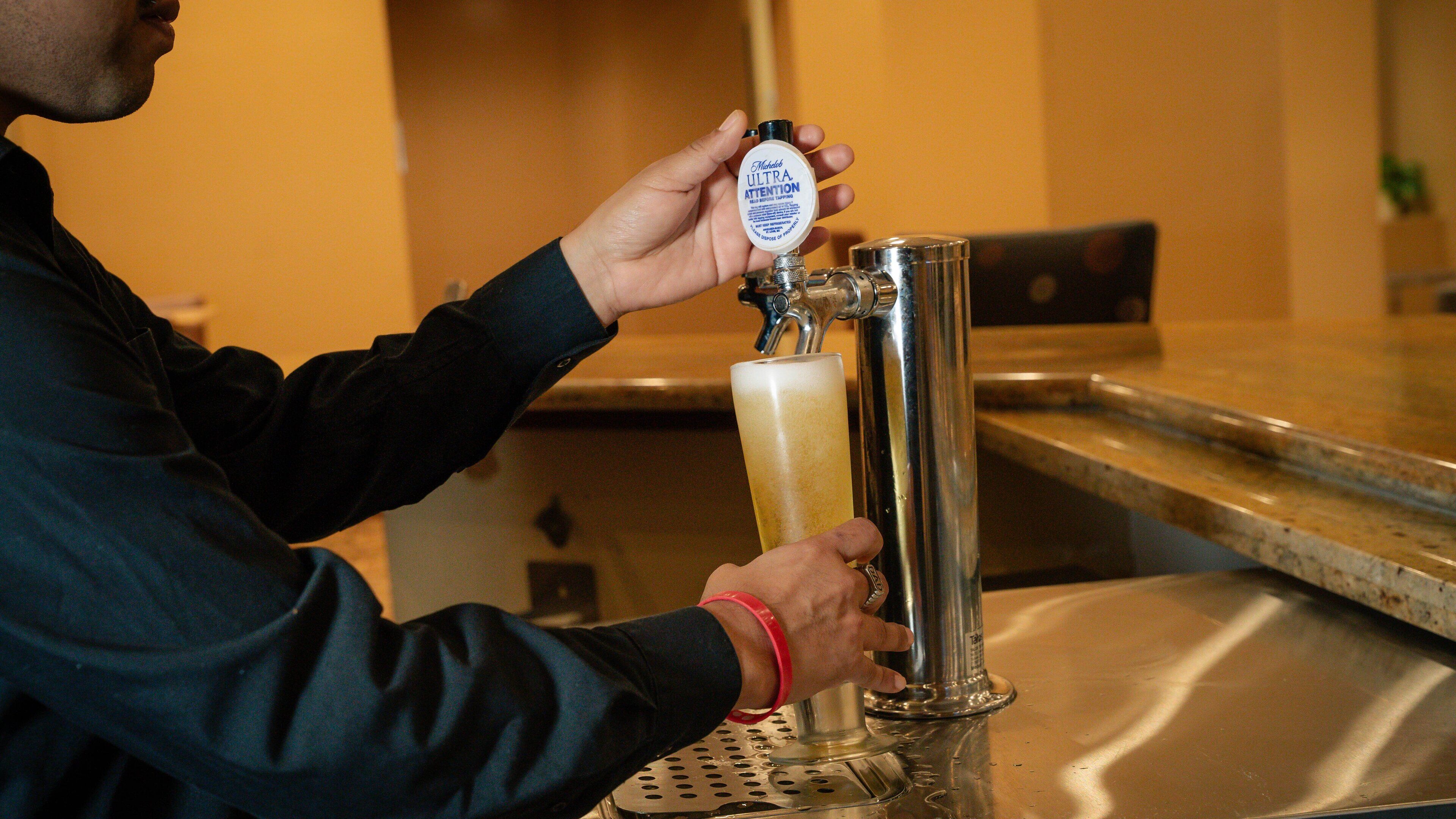 A person pouring beer from a tap into a glass.