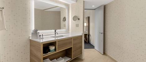 Un baño moderno con tocador de madera, un espejo grande y una ducha a ras de suelo.
