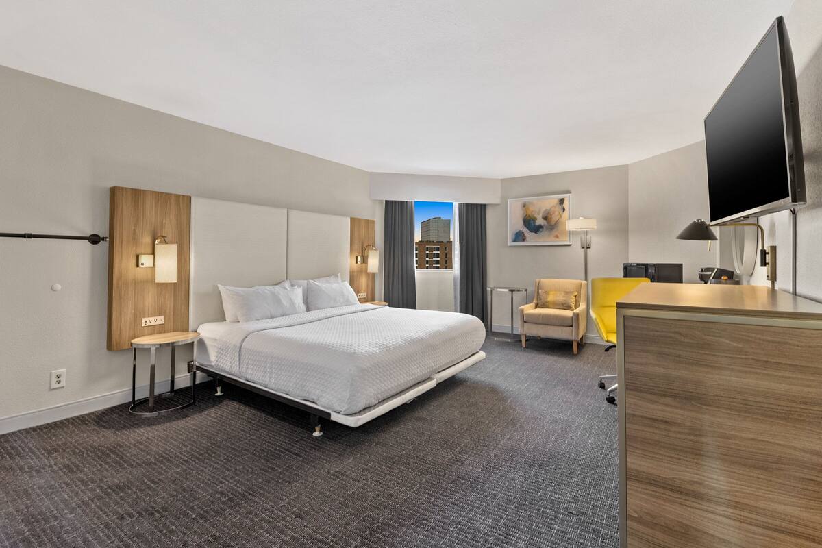Een moderne hotelkamer met een groot bed, een bureau, een stoel en een televisie.