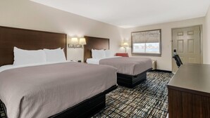 A hotel room with two beds, a desk, and a window with a view. - Quality Inn & Suites Near Six Flags and Medical Center (San Antonio)