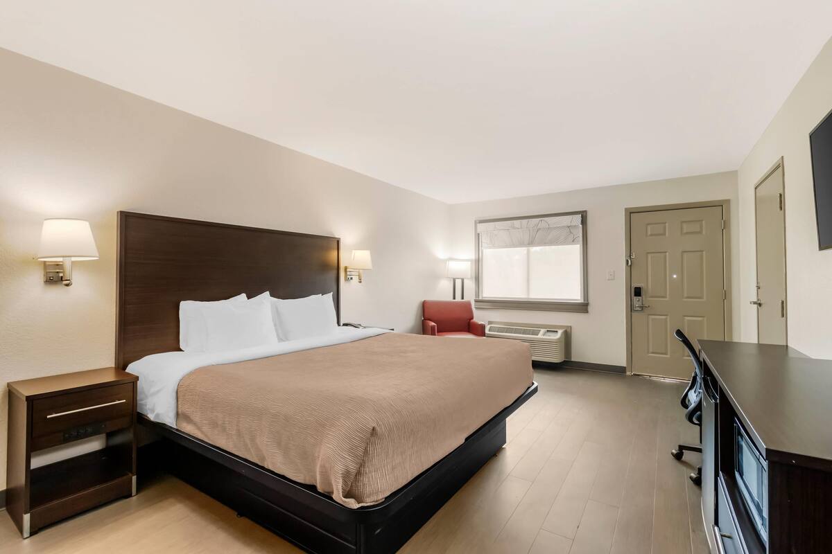 Una camera d'albergo con un letto grande, comodini, una scrivania e una sedia.