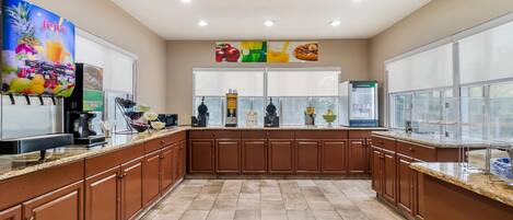 A modern kitchen with brown cabinets, a coffee machine, and a juice dispenser.