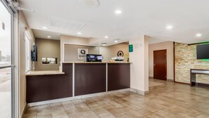 A reception area with a counter, a digital screen, and a sign that reads "Quality". - Quality Inn & Suites Near Six Flags and Medical Center (San Antonio)