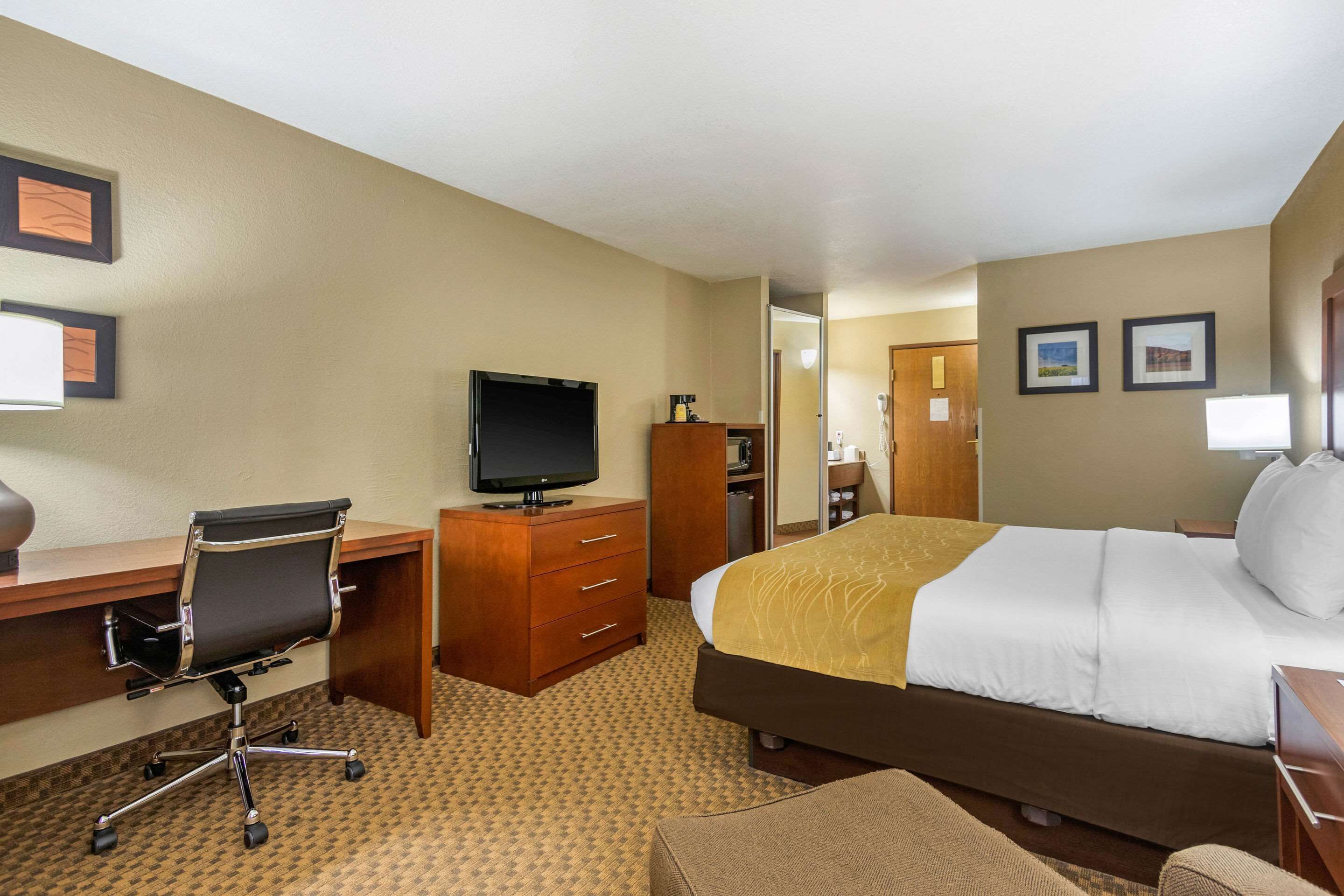 Ein Hotelzimmer mit Bett, Schreibtisch mit Stuhl, Fernseher und Kleiderschrank.