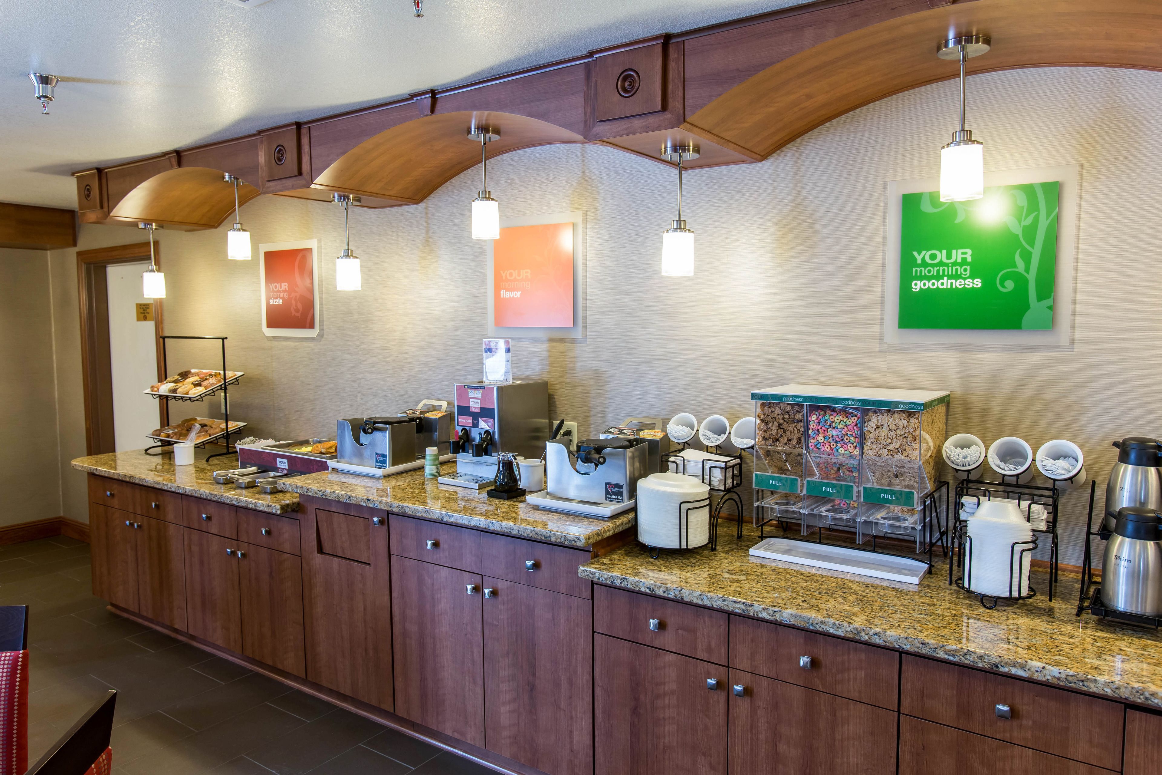 A hotel breakfast area with a counter, coffee machines, and a sign that reads "YOUR morning goodness".