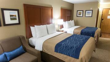 A hotel room with two beds, a sofa, and a desk.