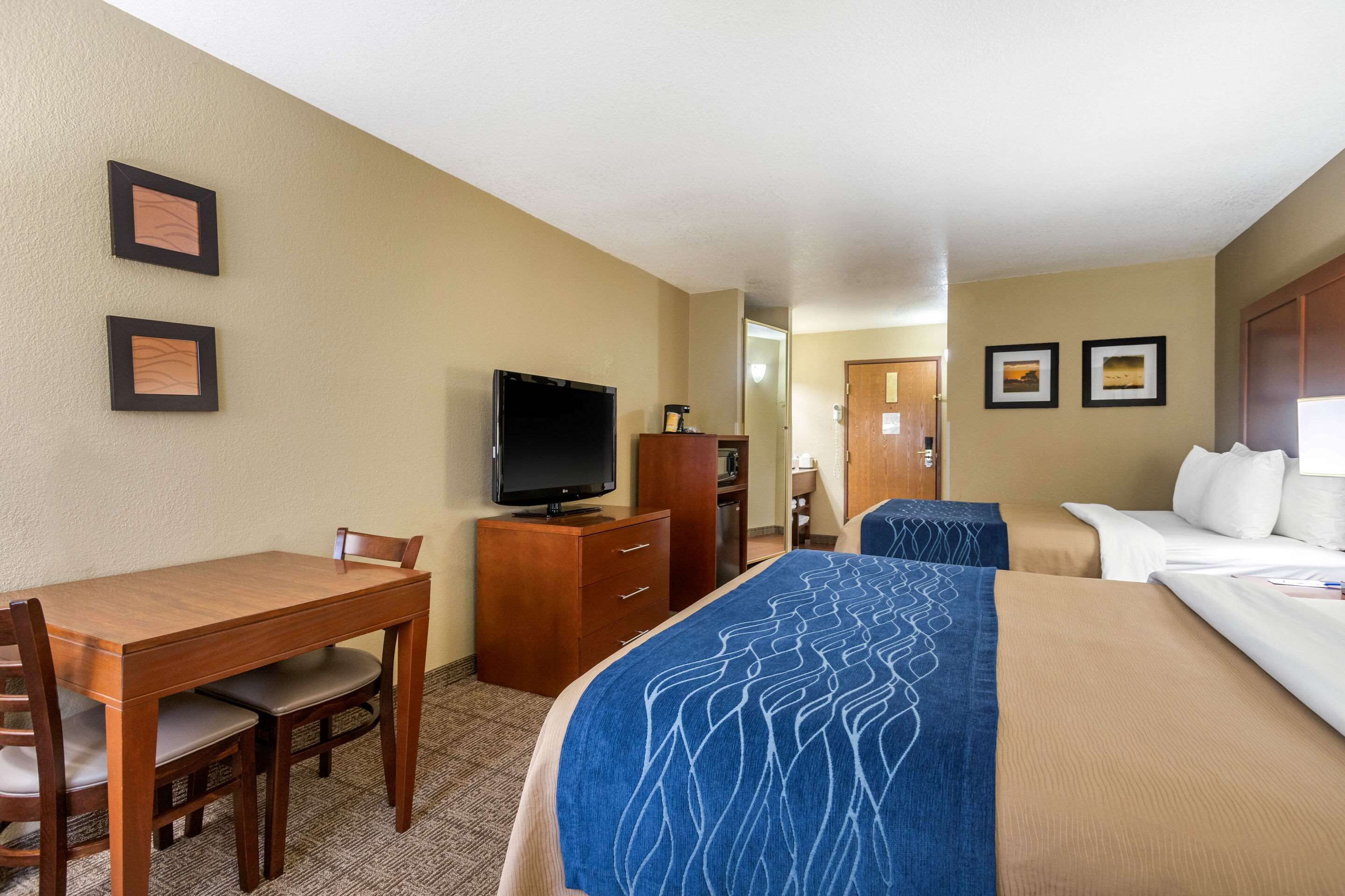 A hotel room with a bed, a desk with a chair, a television, and a wardrobe.