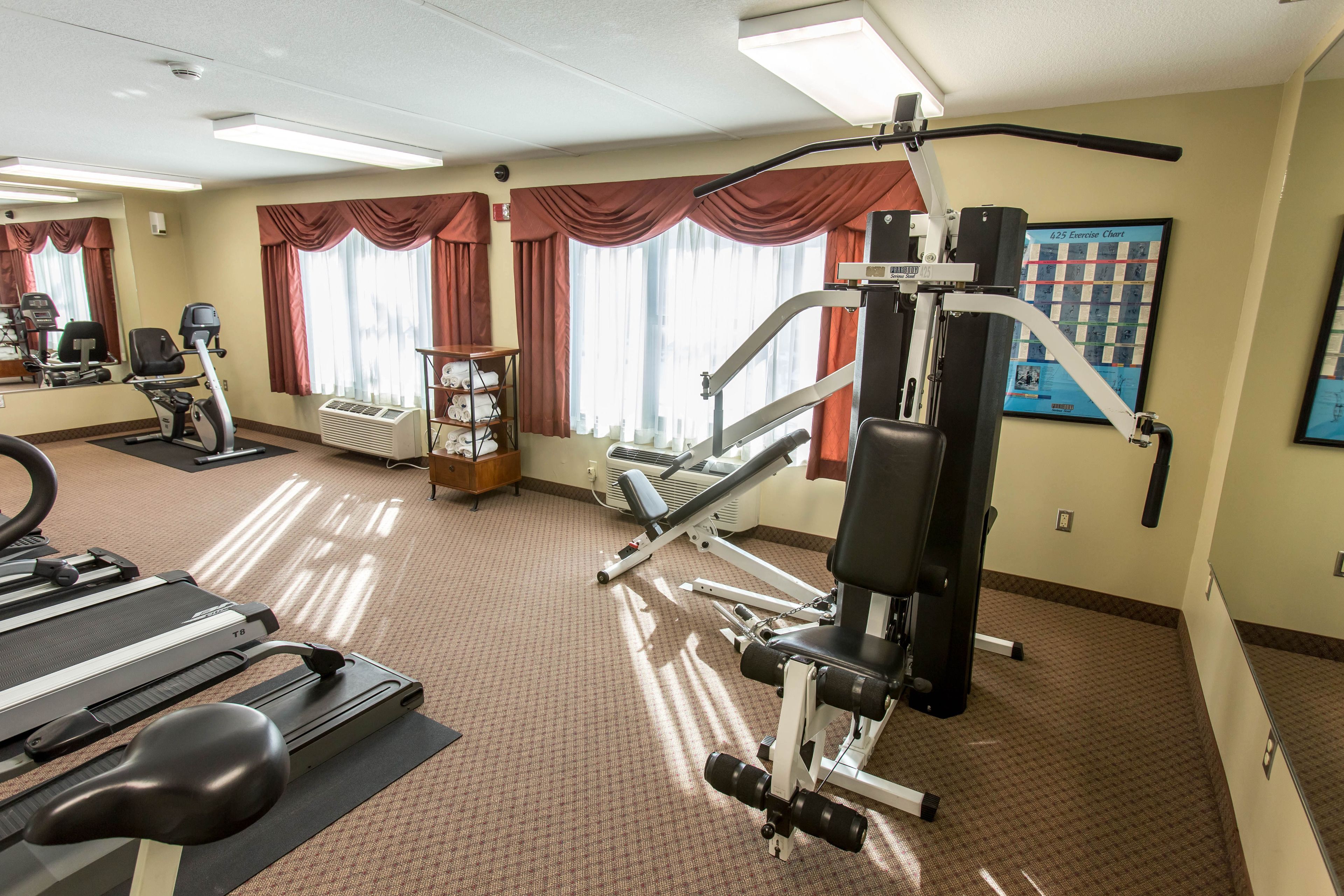 A gym with exercise equipment, a treadmill, and a mirror.