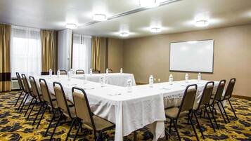 A conference room with a long table, chairs, water bottles, and a whiteboard.