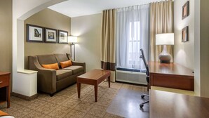 A hotel room with a sofa, a small table, a desk, a lamp, and a window with curtains. - Comfort Inn & Suites Springfield I-44 (Springfield)