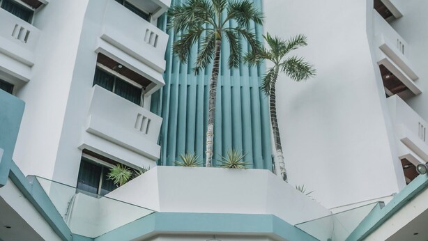 Un hotel moderno con un diseño arquitectónico único, que destaca por una entrada imponente y una fuente decorativa.