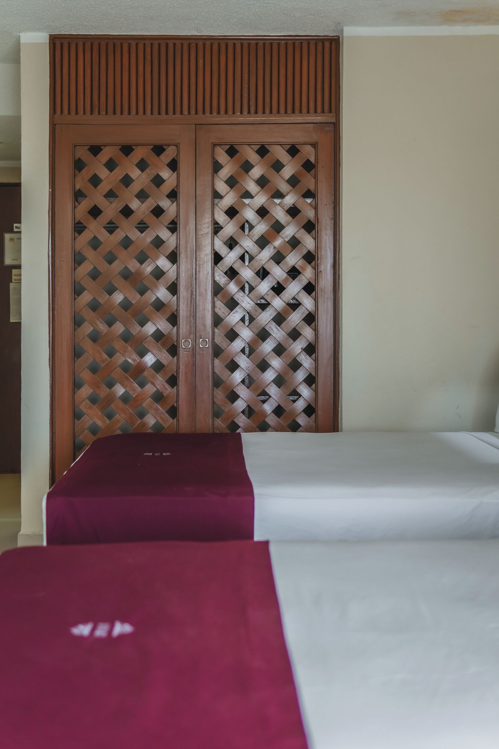 Una habitación con una cama, un armario de madera y una colcha roja y blanca.