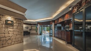 Un vestíbulo amplio con una pared de piedra, una puerta de cristal que da al exterior y una cocina moderna con armarios de madera.