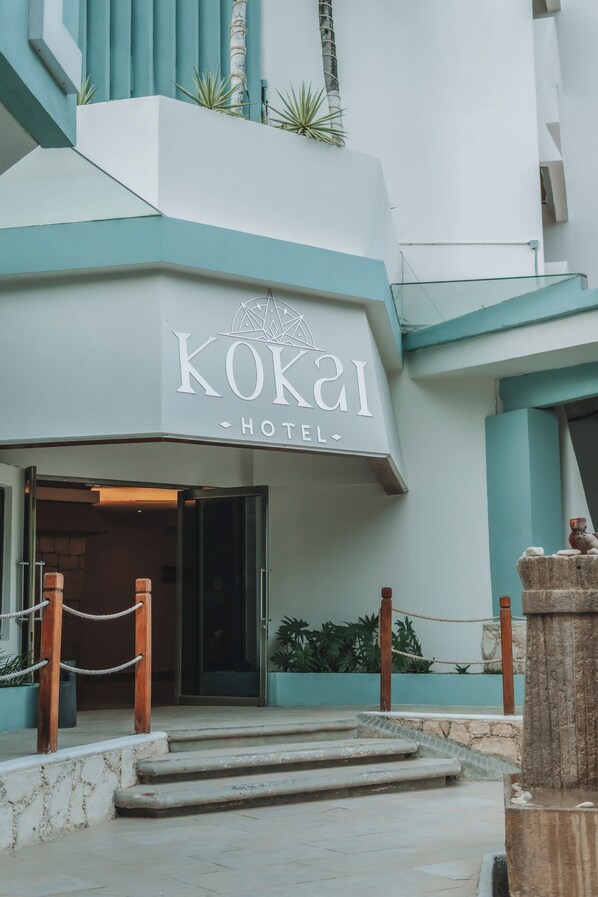 The exterior of KOKAI HOTEL with a modern design, featuring a prominent entrance and a staircase leading to the lobby.