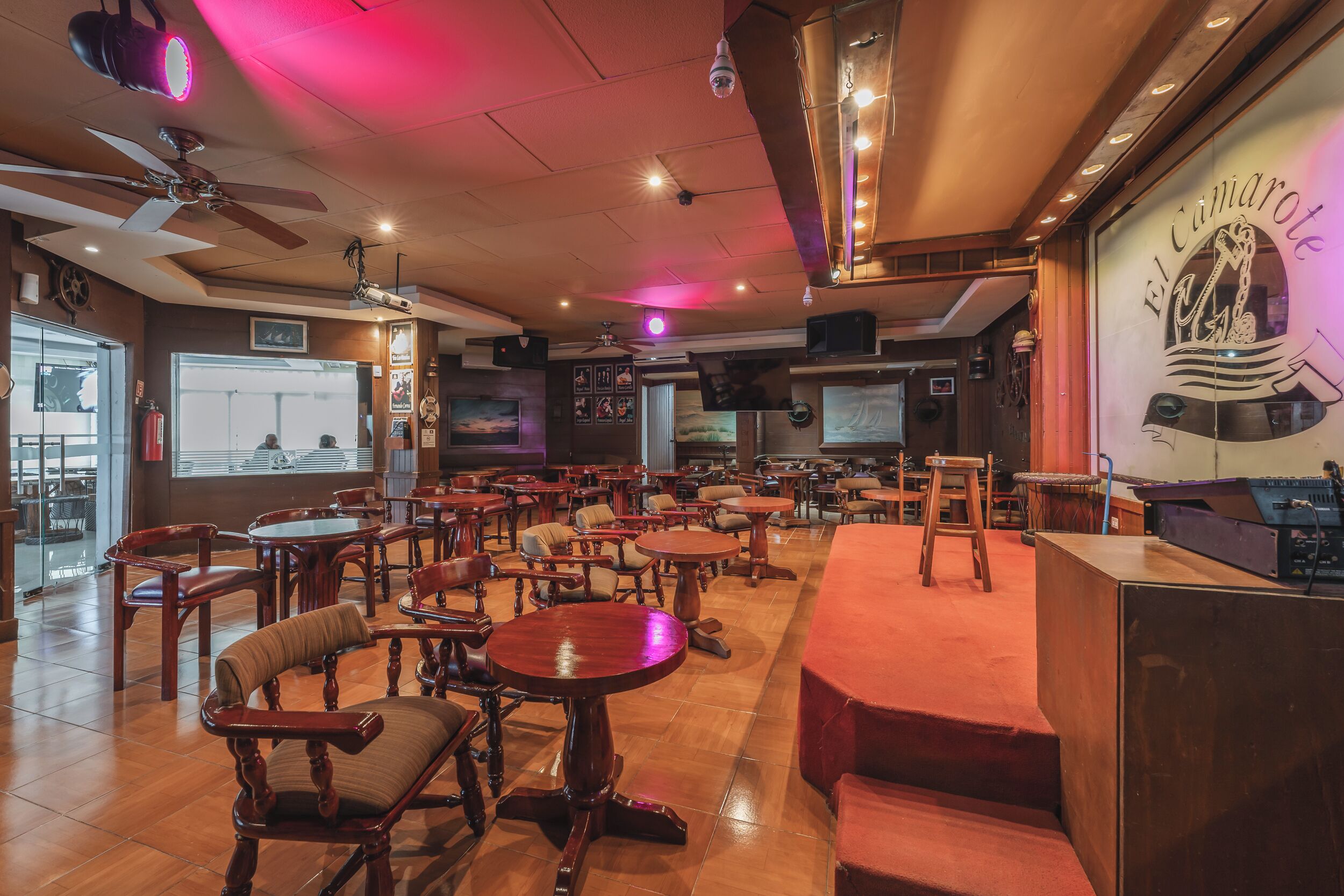 A restaurant with wooden tables and chairs, a bar area, and a large window with a view.