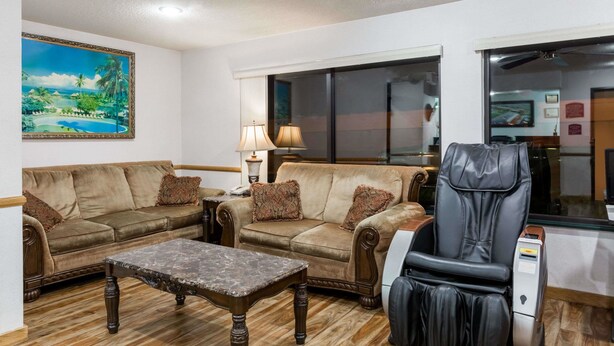A living room with two sofas, a coffee table, and a massage chair. - Howard Johnson by Wyndham Wichita Airport (Wichita)