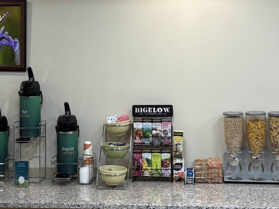 En kaffestation med behållare för vanligt kaffe och varmt vatten, ett ställ med Bigelow-te och olika sorters te- och kaffeburkar.