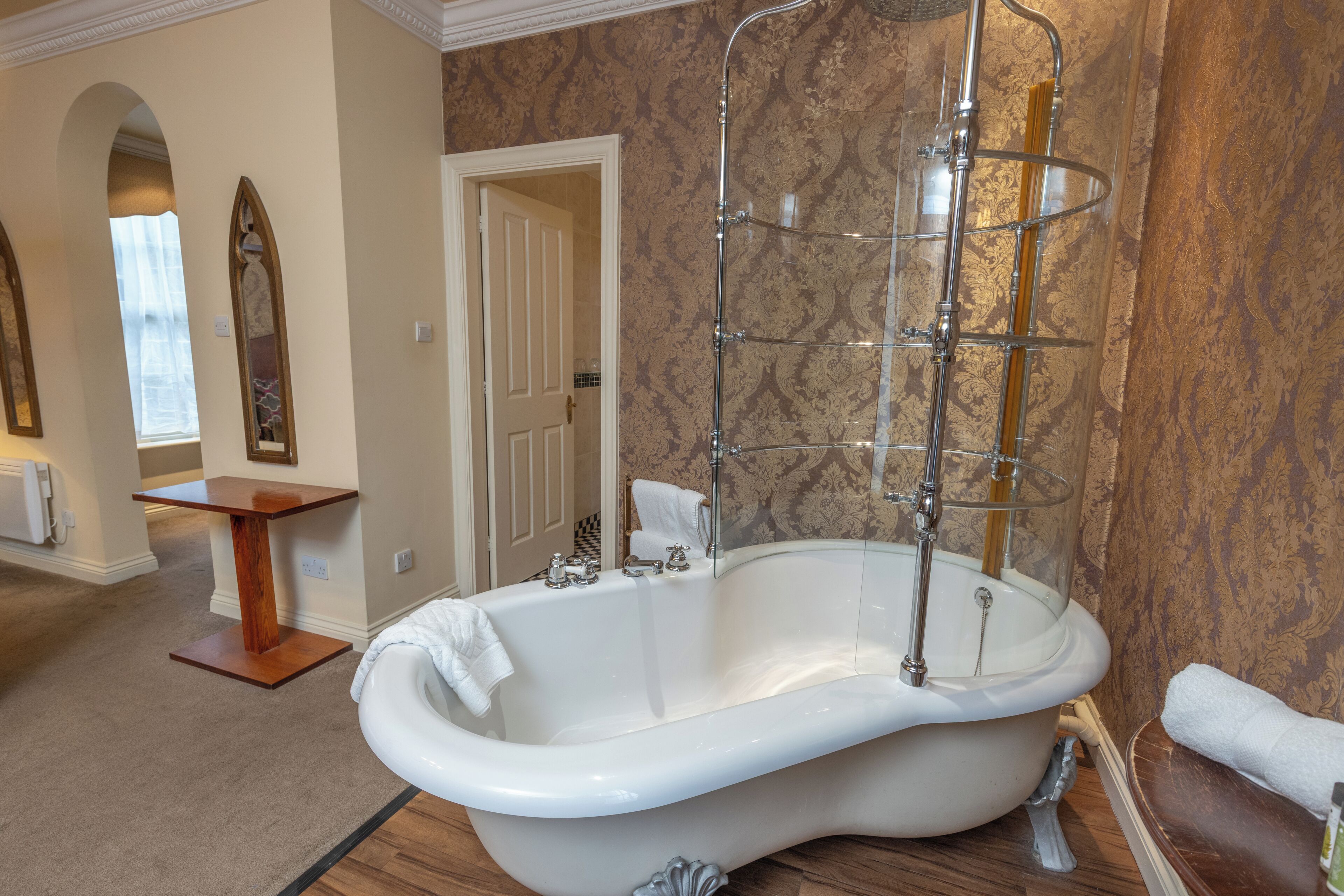 Une salle de bain spacieuse avec une baignoire îlot, une douche à parois de verre et un meuble-lavabo en bois.
