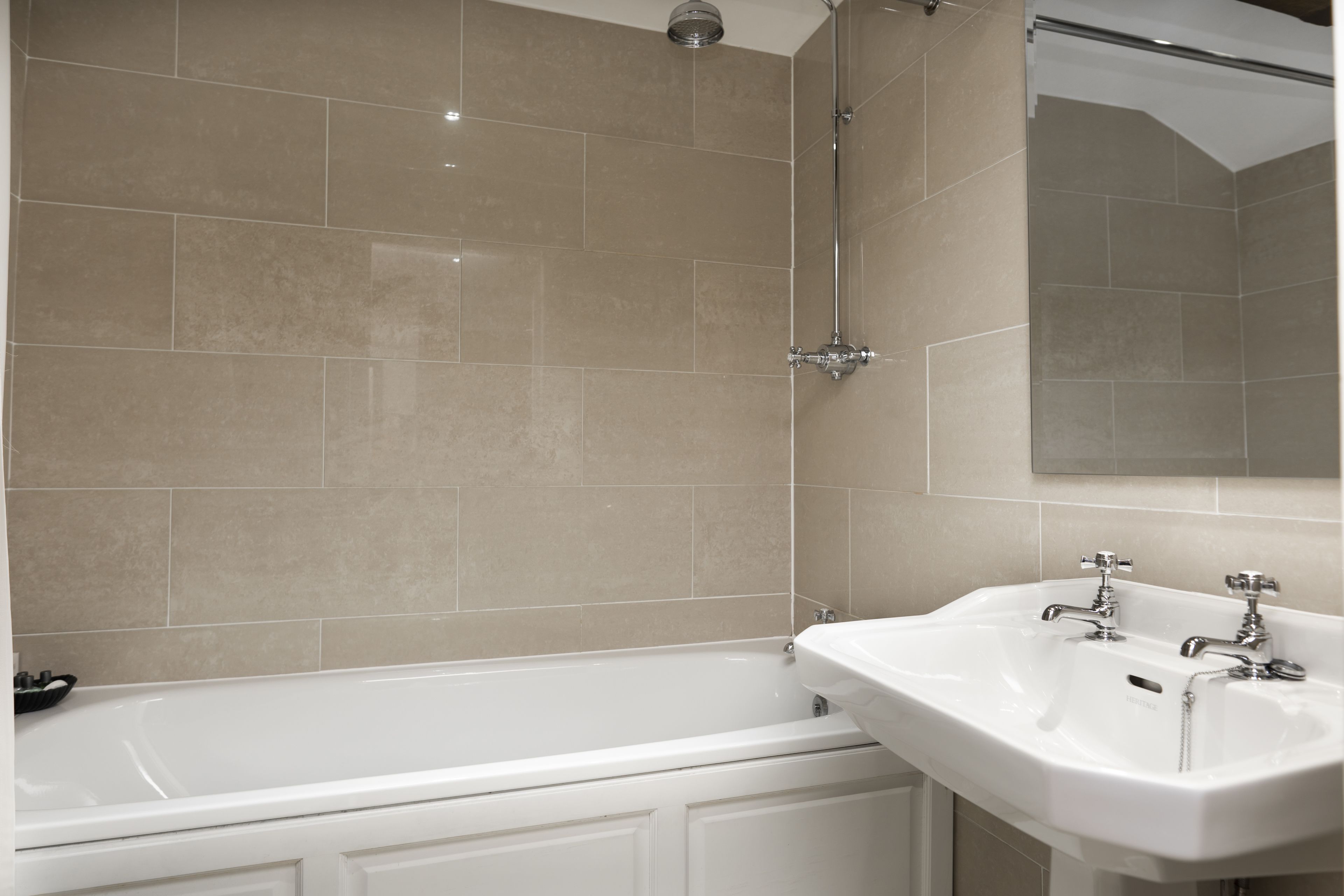 A bathroom with a bathtub, a sink, and a mirror.