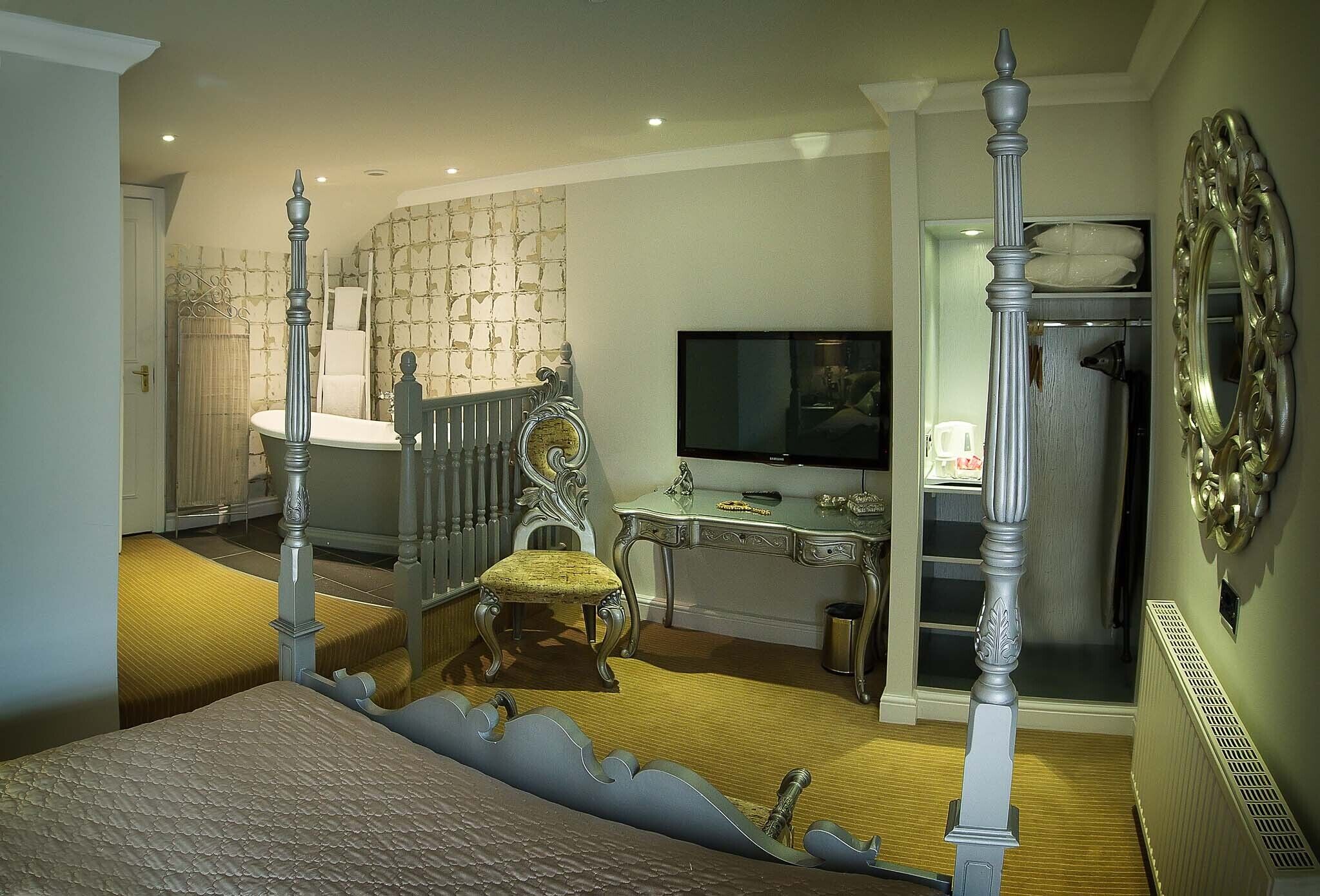 Un dormitorio con cama con dosel, un escritorio con televisor y un armario.