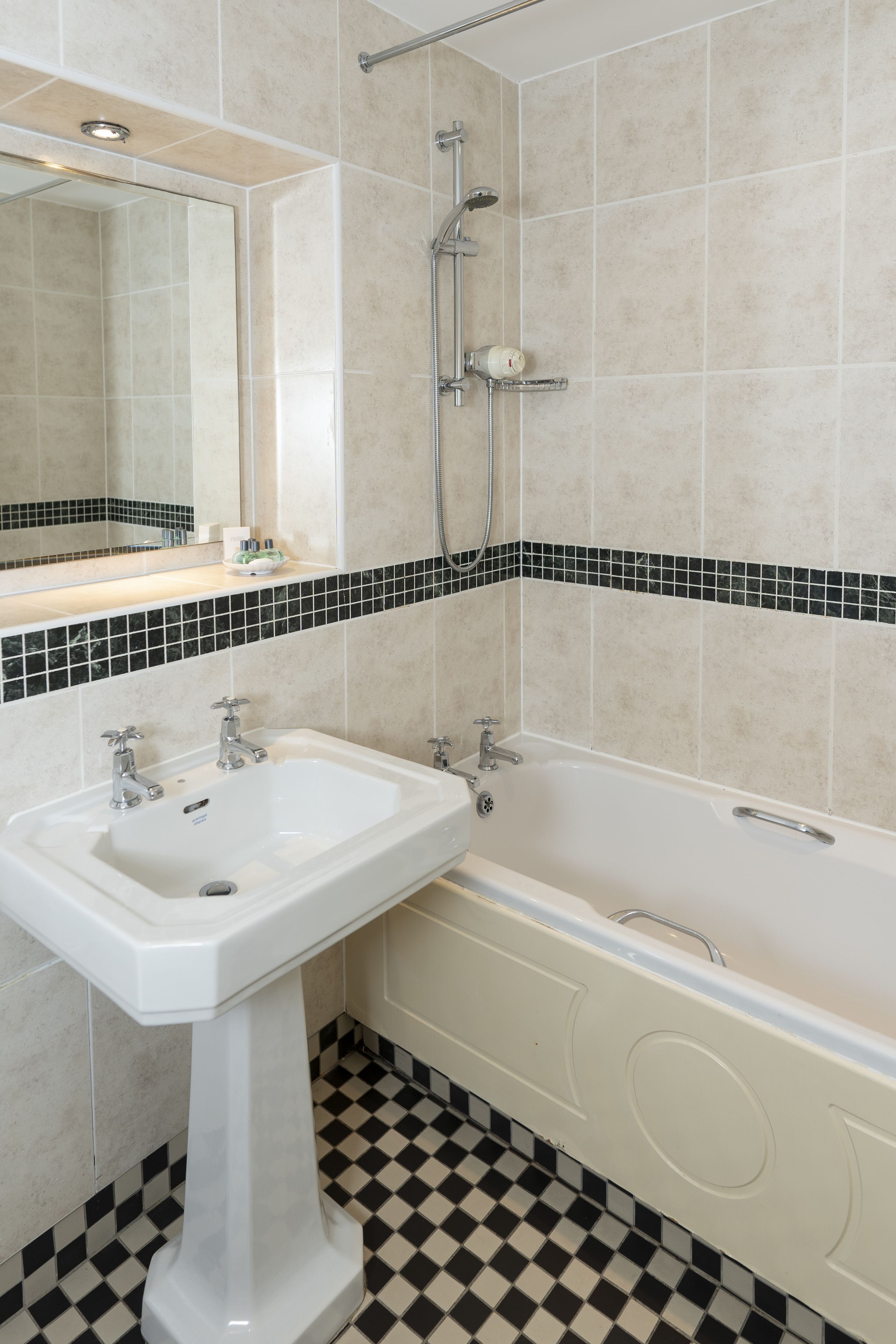 A bathroom with a white sink, a bathtub, and a shower. The floor has a black and white checkered pattern.