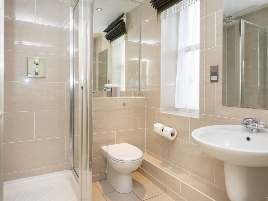 A modern bathroom with a glass shower enclosure, a white toilet, and a pedestal sink.