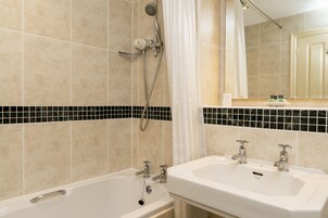Un baño con bañera, dos lavamanos, ducha y salpicadero de azulejos.