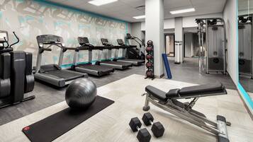 A gym with treadmills, a bench press, and free weights.