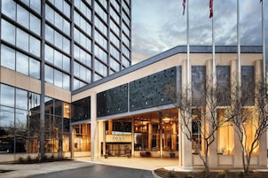 A modern building with a large glass facade, a prominent entrance with a number sign, and a flagpole.