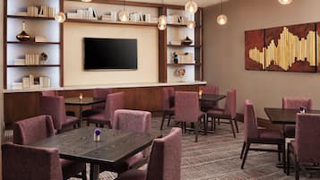 A hotel room with a flat-screen TV, bookshelves, and seating areas.