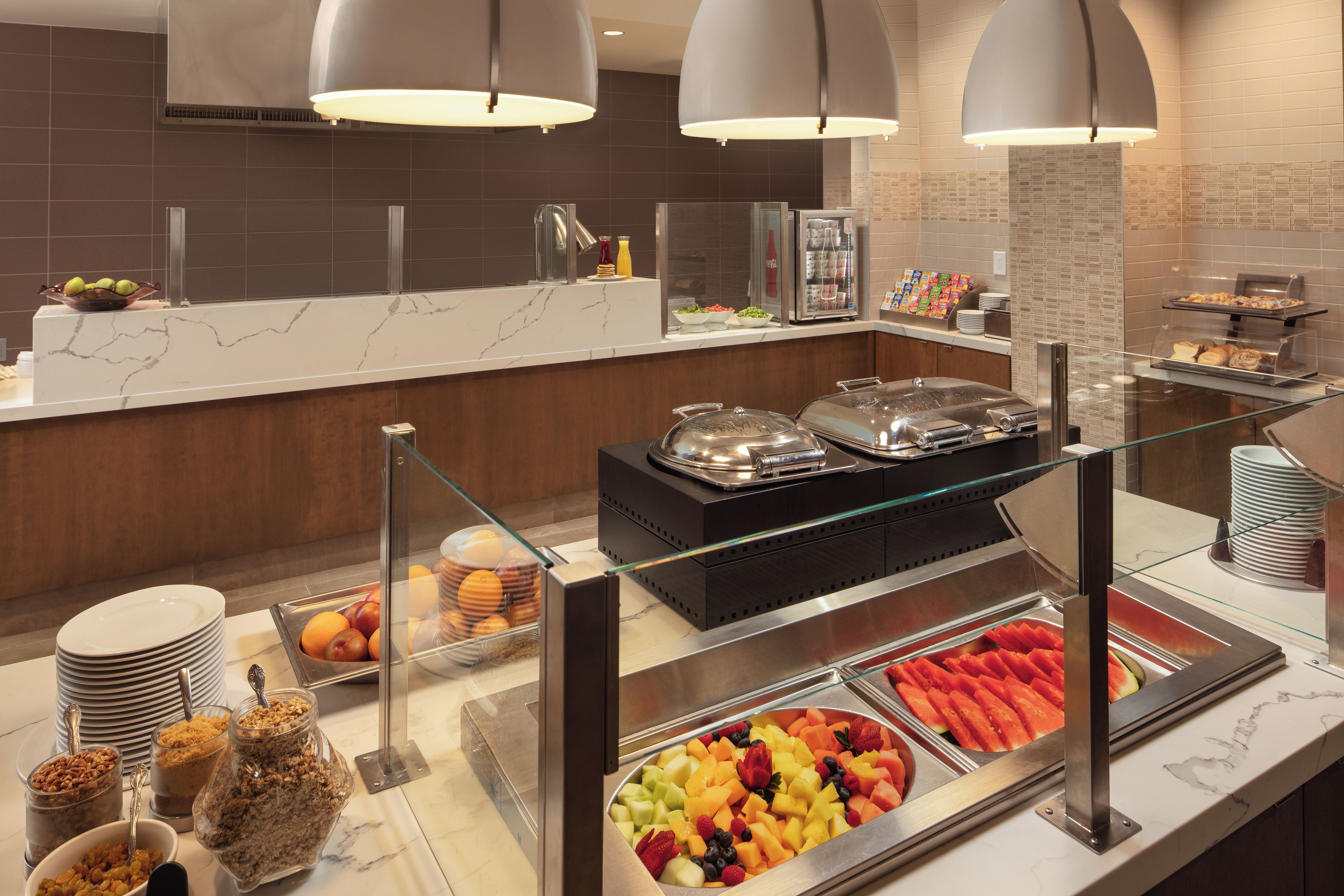 A buffet area with various food options, including fruits, cereals, and beverages.