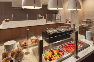 Een buffetgedeelte met diverse eetopties, zoals fruit, ontbijtgranen en drankjes.
