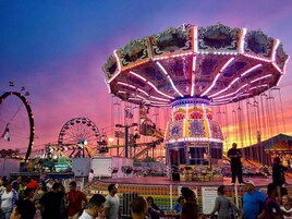 A carousel with ornate decorations and lights, surrounded by a crowd of people.