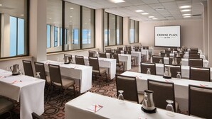 A conference room with multiple tables, chairs, and a projection screen displaying "CROWNE PLAZA BY IHG". - Crowne Plaza Dallas Market Ctr - Love Field by IHG (Dallas)